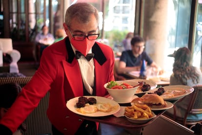 A waiter with several servings of eggs with blood sausage, salad and chistorra sandwich with Idiazábal