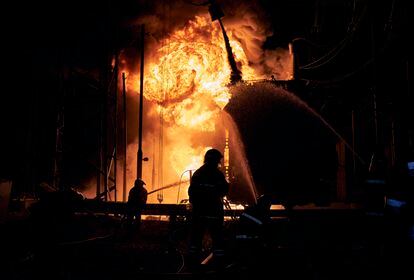 Los bomberos ucranios apagan un incendio después de que un ataque con cohetes rusos golpeara una central eléctrica en Járkov, este domingo. 
