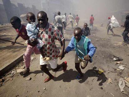 Un hombre conduce ayer a un grupo de niños fuera del suburbio de Mathare, en Nairobi, tras varios días de violencia.