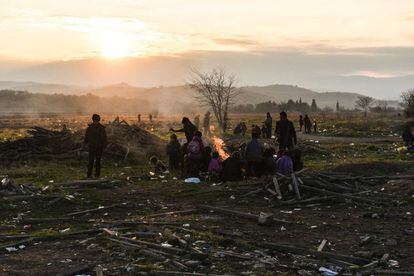 Un grupo de inmigrantes sentados alrededor de una hoguera mientras esperan para entrar en el campamento de refugiados después de cruzar la frontera Macedonio Griego, cerca de Gevgelija.