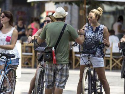 Cuatro turistas en bicicleta escuchan las indicaciones de su gu&iacute;a en el centro hist&oacute;rico de Valencia. EFE/Archivo