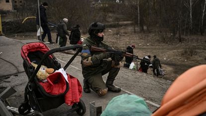 Las tropas ucranias cubren a los ciudadanos que son evacuados de la ciudad de Irpin, cerca de Kiev, el domingo.