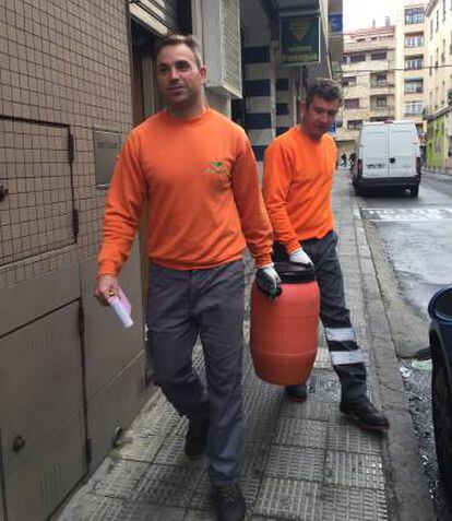 Dos trabajadores de la cooperativa Porsiete recogen aceite vegetal usado.