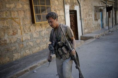 Un rebelde, cubierto de polvo, camina tras escapar de un edificio derribado por el Ejército sirio.