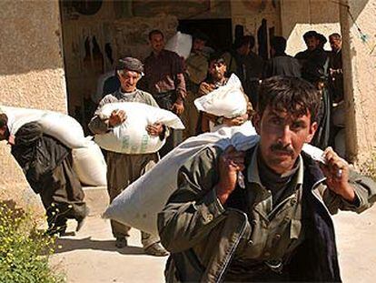 Milicianos kurdos se llevan sacos de arroz de un almacén del Ejército de Irak, ayer, en las afueras de la ciudad de Kirkuk.