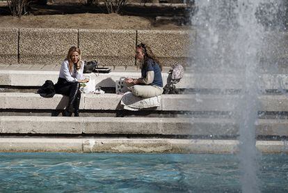 Dos mujeres disfrutan del sol en un parque de Madrid