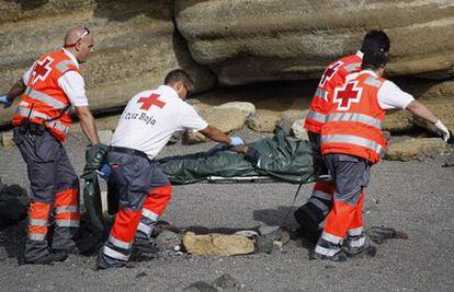 Miembros de la Cruz Roja trasladan el cadáver del inmigrante muerto en la playa de Granadilla (Tenerife).