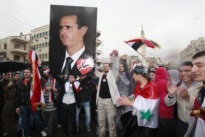 Simpatizantes del régimen de Bachar el Asad alzan su retrato en una manifestación en Damasco (Siria).