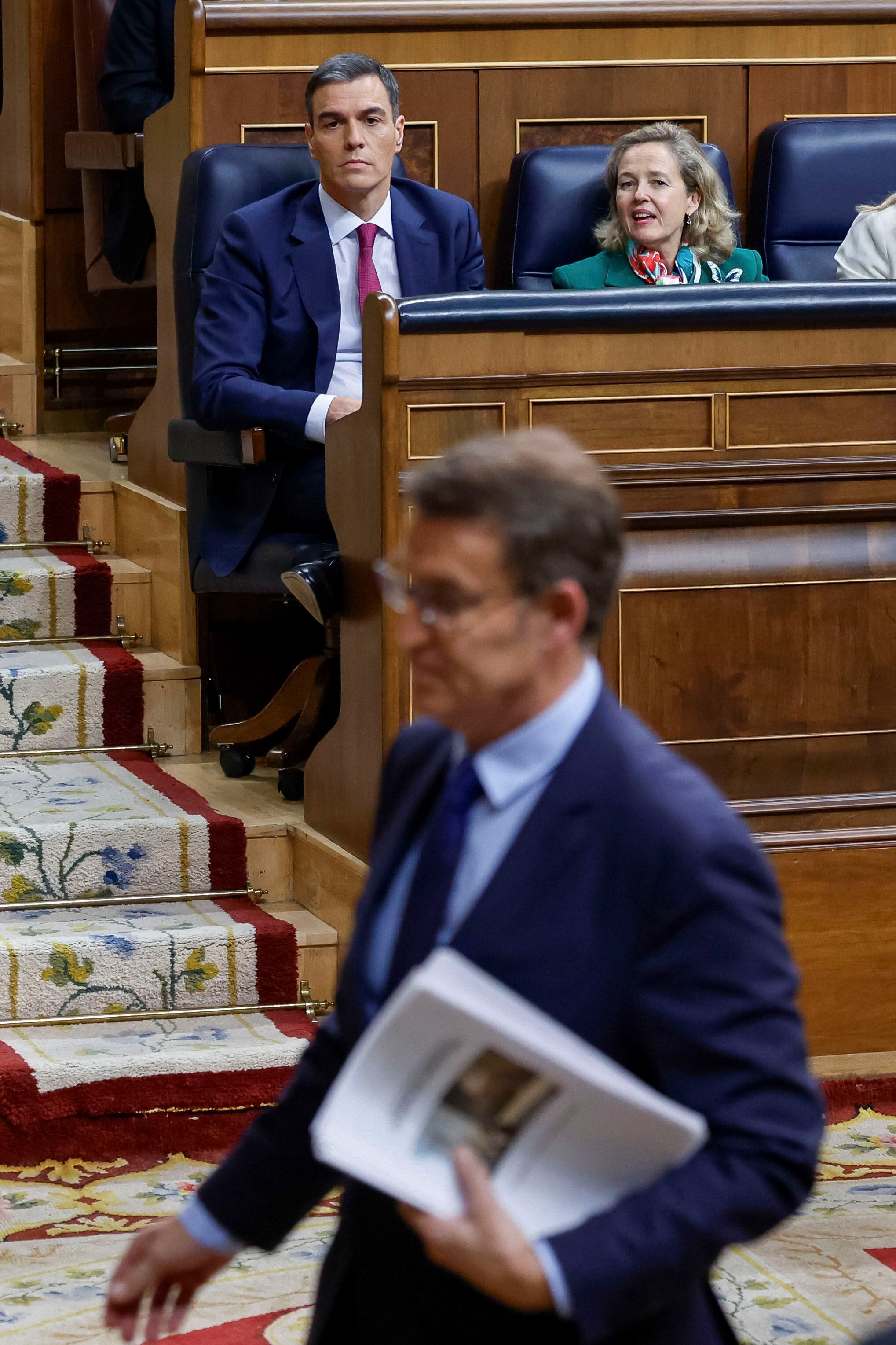 El candidato del PSOE a la investidura, Pedro Sánchez, y la vicepresidenta primera en funciones, Nadia Calviño, observan cómo Alberto Núñez Feijóo se dirige al estrado para dar la réplica al discurso del socialista. 