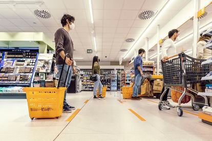 Compradores haciendo cola para pagar en un supermercado.