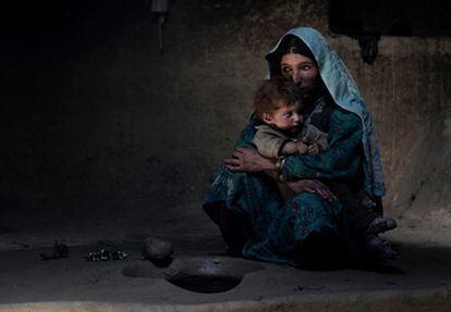 Una madre adicta al opio consuela a su hijo de un año, que llora día y noche, en una imagen de 2009. Cuando le echa humo en la cara, el pequeño se duerme. Viven en la montañosa y remota aldea de Sarab (Afganistán).