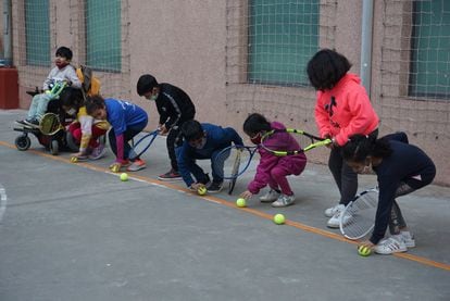 Un grupo de niños juegan con raquetas y pelotas en el Centro Socioeducativo Poble-sec (Barcelona), que ofrece clases gratuitas de tenis a niños que habitualmente no tienen acceso a este deporte. 