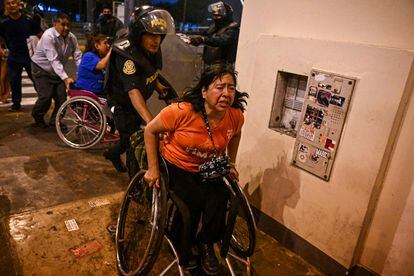 Varias personas se protegen de los gases lacrimógenos lanzados por la policía durante los enfrentamientos en Lima.