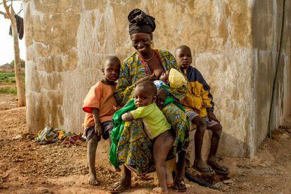 Una madre amamanta a su hijo menor en compañía del resto de hermanos en el jardín de mujeres de Kolonia, en Malí.
