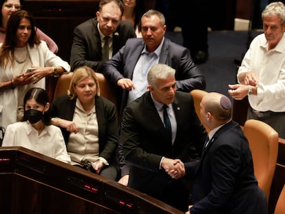 El ministro de Asuntos Exteriores israelí, Yair Lapid (segundo por la derecha) y el primer ministro saliente, Naftali Bennett, se estrechan la mano, este jueves en el Parlamento de Israel, en Jerusalén.