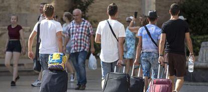 Cuatro turistas caminan con su maletas por Valencia.