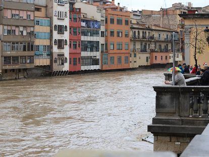 Vecinos de Girona observan una crecida del río Onyar a su paso por la ciudad.