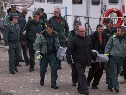 Guardias civiles portan el cadáver del patrón en el puerto de Ribeira