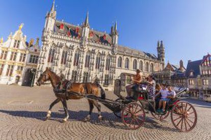 Turistas en un coche de caballos en el Burg, la playa del Ayuntamiento, en Brujas.
