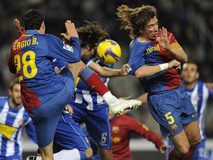 Sergio Busquets y Puyol intentan despejar ante Román.