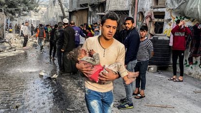 Un ciudadano palestino traslada a una niña herida tras un ataque israelí que ha alcanzado una vivienda este viernes en Gaza.