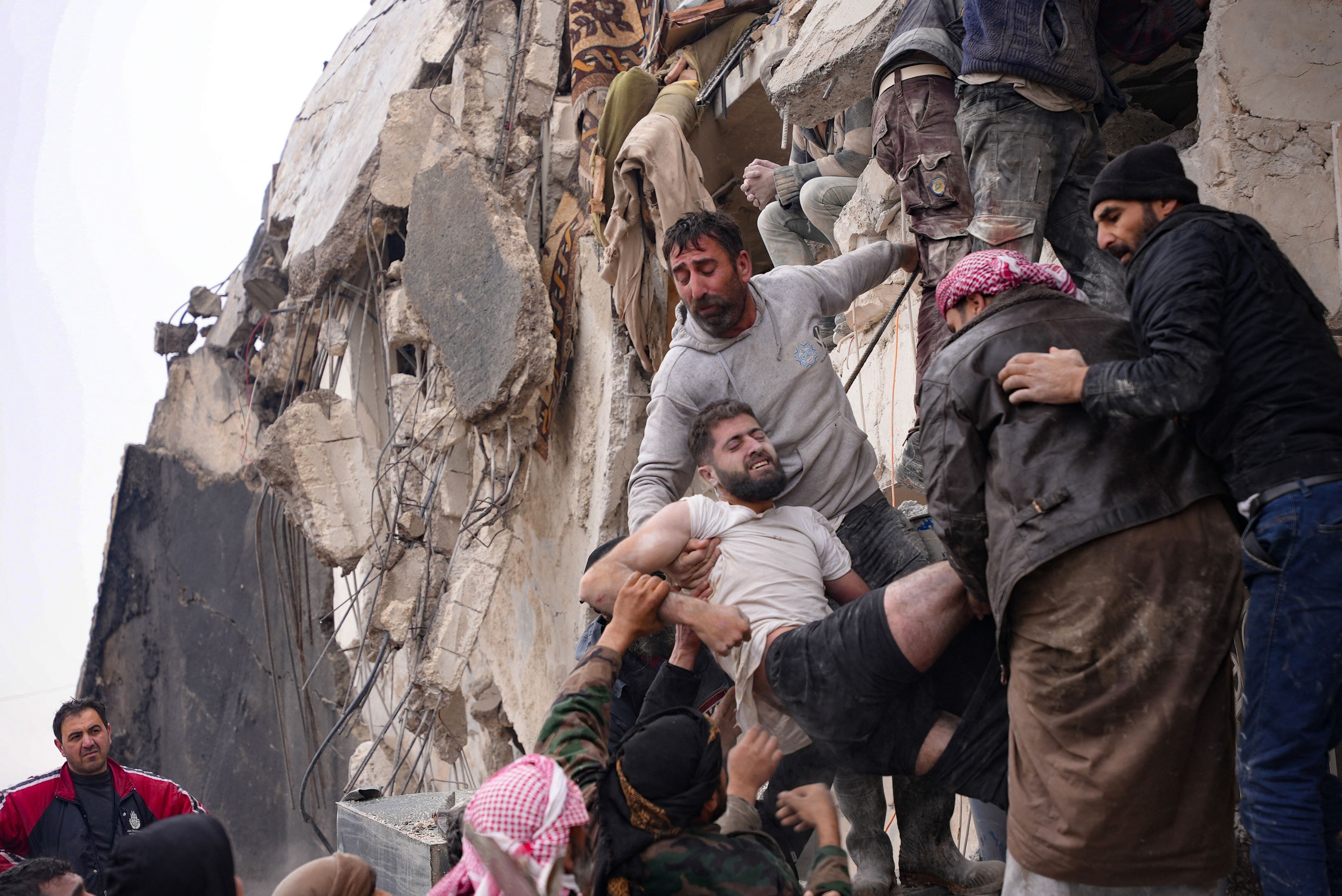 TOPSHOT - Residents retrieve an injured man from the rubble of a collapsed building following an earthquake in the town of Jandaris, in the countryside of Syria's northwestern city of Afrin in the rebel-held part of Aleppo province, on February 6, 2023. - Hundreds have been reportedly killed in north Syria after a 7.8-magnitude earthquake that originated in Turkey and was felt across neighbouring countries. (Photo by Rami al SAYED / AFP)