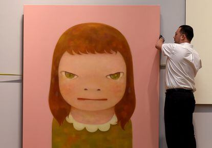 Un trabajador cuelga la obra Yoshitomo Nara  "Wish World Peace", en 2016 en Sothebys New York.