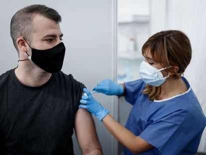 Una enfermera vacuna de la tercera dosis a un joven en Barcelona.