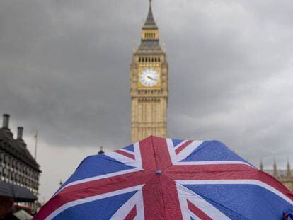 Una persona con un paraguas con la bandera de Reino Unido, delante del parlamento brit&aacute;nico.