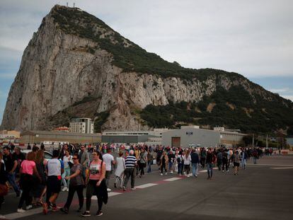 Peatones cruzan la pista en el aeropuerto de Gibraltar, con el peñón al fondo.