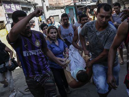 Un grupo de personas carga el cuerpo de un hombre durante un operativo policial, en una favela de Río de Janeiro.