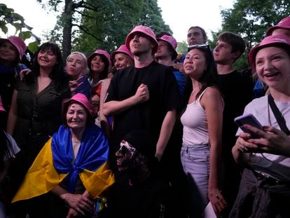 El líder de la banda ucrania Kalush Orchestra, Oleh Psiuk, se encuentra con un grupo de compatriotas que lucen su característico gorro rosa ante el recinto Pala Alpitour de Turín (Italia).