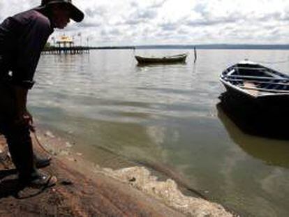 Un hombre observa el agua contaminada de la orilla del lago Ypacaraí en la localidad de Areguá (Paraguay). EFE/Archivo