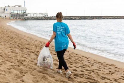 Una voluntaria del proyecto Silmar, del centro comercial Diagonal Mar de Barcelona, retira basura de una playa.
