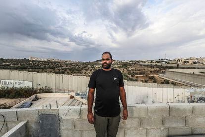 Ali Abu Aker, de 36 años, asomado a la azotea de su casa delante del muro. “Es como si no hubiera salido de la cárcel”. Tras nueve años en prisiones de Israel, regresó a Aida el pasado marzo.