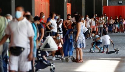 Numerosas personas hacen cola en los bajos del estadio de Mestalla, donde acuden a recibir ayuda por parte del banco de alimentos.