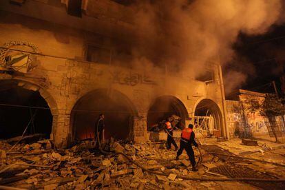 Bomberos palestinos tratan de apagar el fuego ocasionado tras el ataque a&eacute;reo israel&iacute; contra la sede del Banco Nacional en la ciudad de Gaza.