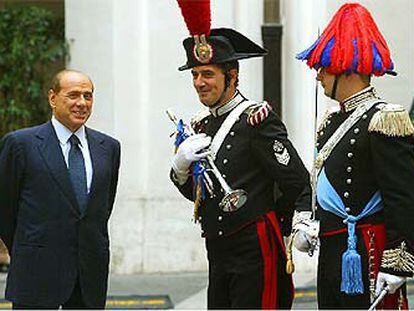 Berlusconi charla con dos <i>carabinieri</i> en traje de gala mientras espera a Abdalá de Jordania, en Roma.