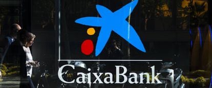 Dos personas pasando por delante de una oficina de CaixaBank en Barcelona