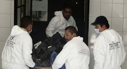 Los forenses sacan las bolsas con los cadáveres.