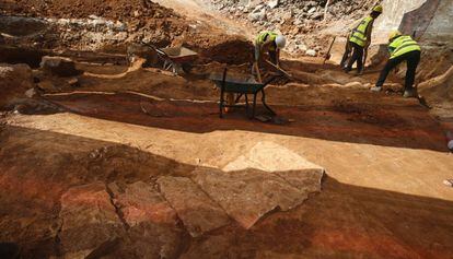 Una de las 16 tumbas ya excavadas, en primer plano. Al fondo, tres arqueólogos trabajan otra de las fosas.