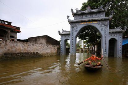 Un niño rema a bordo de una pequeña embarcación por las calles de Hanoi (Vietnam), inundadas por las fuertes lluvias causadas por las tomentas tropicales.