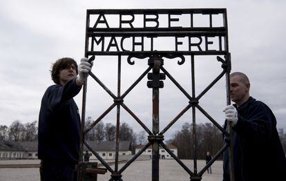 Dos empleados de una empresa de transportes llevan la puerta con la inscripción 'Arbeit macht frei' (El trabajo os hará libres) en el memorial del antiguo campo de concentración nazi en Dachau, (Alemania). La puerta fue robada en 2014 y reapareció en noviembre de 2016 cerca de la ciudad de Bergen, en Noruega.