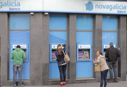 Varios usuarios de los cajeros en una sucursal de Novagalicia Banco, en Santiago de Compostela.