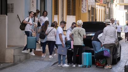 Varios jóvenes cargados con maletas salen de un piso turístico en Sevilla.