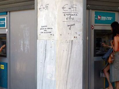 Dos ciudadanas sacan dinero de un cajero autom&aacute;tico en Atenas.
