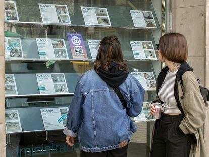 Dos personas observan la oferta de pisos en alquiler de una oficina inmobiliaria de Barcelona.