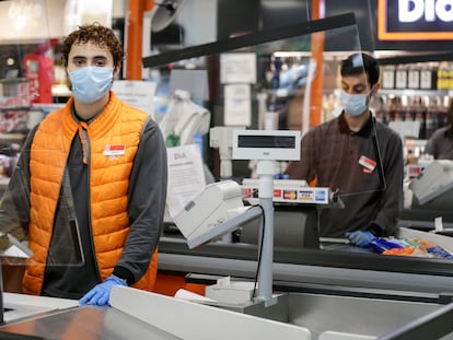 Adrián, 21, estudiante y empleado de un supermercado Día & Go en Madrid posa junto a las cajas.