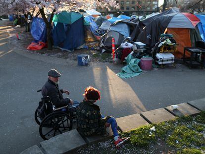 Dos personas conversan cerca de un campamento de sin techo en el Parque Oppenheimer de Vancouver, Canadá, en abril de 2020.