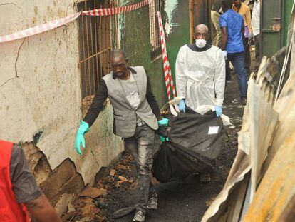 Dos personas transportan un cadáver tras el incendio en Monrovia, este miércoles en Monrovia.